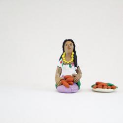 Kneeling Muñeca in White and Purple Dress with Carrots and Plate of Carrots