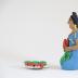 Kneeling Muñeca in Blue Dress with Carrots and Plate of Carrots